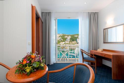 ein Hotelzimmer mit einem Schreibtisch und einem Tisch mit Blumen darauf. in der Unterkunft Hotel Vis in Dubrovnik