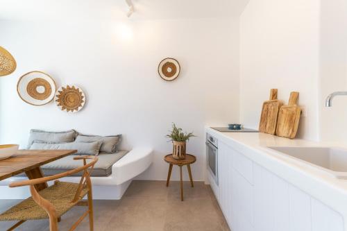 eine Küche mit weißen Wänden, einem Tisch und einem Sofa in der Unterkunft Anemela Villas & Suites Mykonos in Agrari