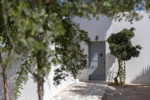 a grey door in a white building with trees at Naxos green Village hotel in Naxos Chora