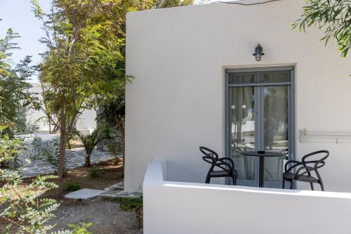 a white house with black chairs on the porch at Naxos green Village hotel in Naxos Chora