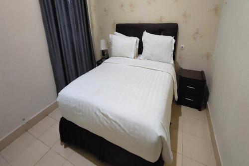 ein Schlafzimmer mit einem großen Bett mit weißer Bettwäsche und Kissen in der Unterkunft SPOT ON 92196 Kost Axcel in Banjarmasin