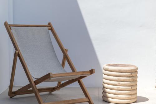 a wooden rocking chair next to a stack of disks at Anemela Villas & Suites Mykonos in Agrari