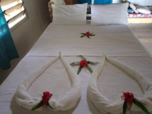 Una cama con sábanas blancas y flores rojas. en Lonnoc Beach Lodge, en Hog Harbour