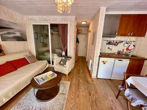 un salon avec un canapé et une cuisine dans l'établissement Niedliche Wohnung mit Terrasse direkt am Strand, à Lège-Cap-Ferret