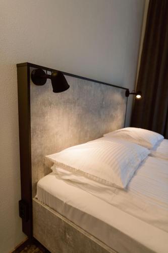 a bed with a head board with a lamp on it at Ošupio Vasarnamis in Šventoji