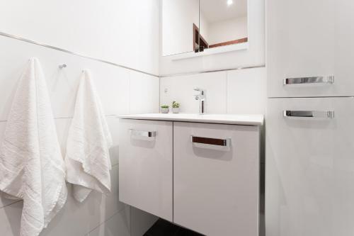 W białej łazience znajduje się umywalka i lustro. w obiekcie Seepark Wohnung 3 2 w mieście Scharbeutz