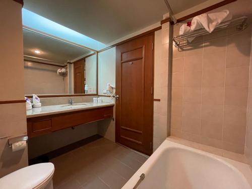 y baño con bañera, aseo y lavamanos. en Songphanburi Hotel, en Suphanburi