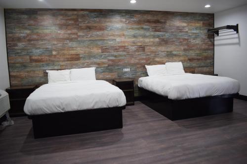 two beds in a room with a brick wall at Hyde Park Motel in Los Angeles