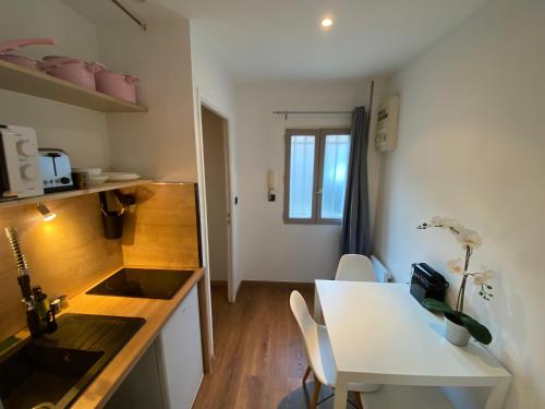 une cuisine et une salle à manger avec une table et des chaises blanches dans l'établissement STUDIO CONFORT ROTONDE*CALME*CLIM*WIFI*SMART TV, à Aix-en-Provence