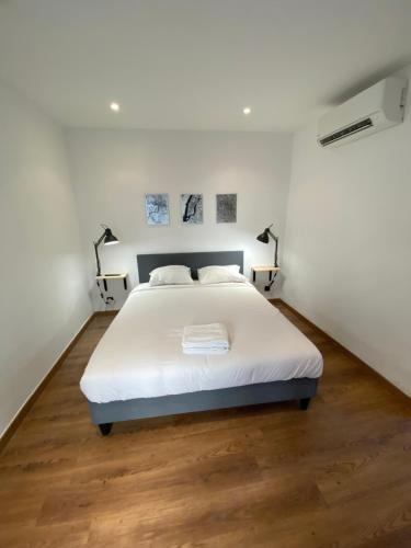 une chambre blanche avec un lit et un parquet dans l'établissement STUDIO CONFORT ROTONDE*CALME*CLIM*WIFI*SMART TV, à Aix-en-Provence