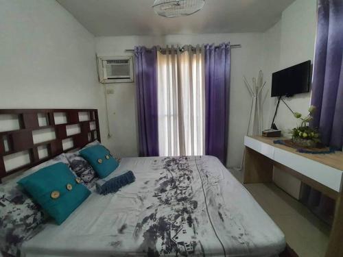 a bedroom with a large bed with blue pillows at Cozy Place 2BR Condo Unit in Ortigas Ave Ext in Cainta
