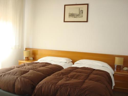 a bedroom with two beds and a picture on the wall at Albergo La Sfinge in Chiusi