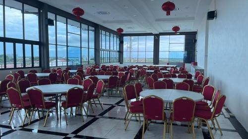 um quarto com mesas, cadeiras e janelas em Wing Tat Grand Hotel em Semporna
