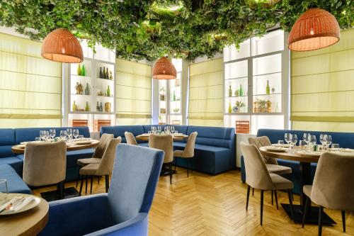 a restaurant with tables and chairs and windows at Grand Mildom Hotel in Almaty