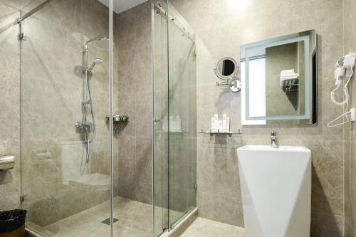 a bathroom with a glass shower with a toilet and a sink at Grand Mildom Hotel in Almaty