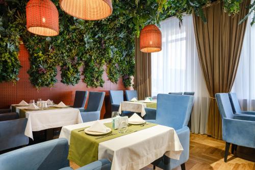 a restaurant with two tables and blue chairs and plants at Grand Mildom Hotel in Almaty