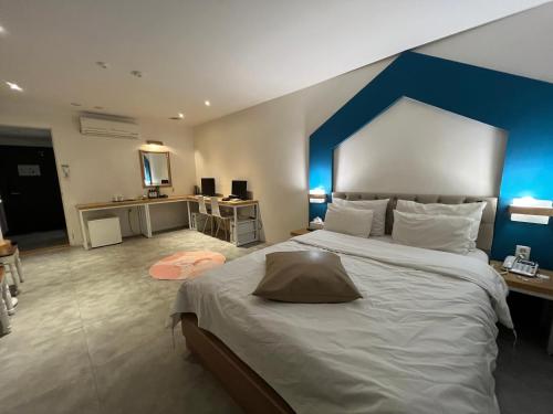 a bedroom with a large bed with a blue headboard at Hotel Yaja Hwajeong Station in Goyang