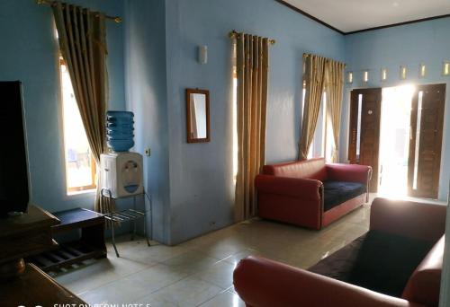 Homestay Putra Sindang Asih Batukaras في Batukaras: غرفة معيشة مع أريكة وكرسي
