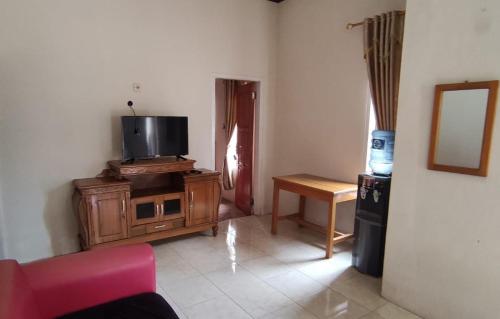 Homestay Putra Sindang Asih Batukaras في Batukaras: غرفة معيشة مع تلفزيون وأريكة وطاولة