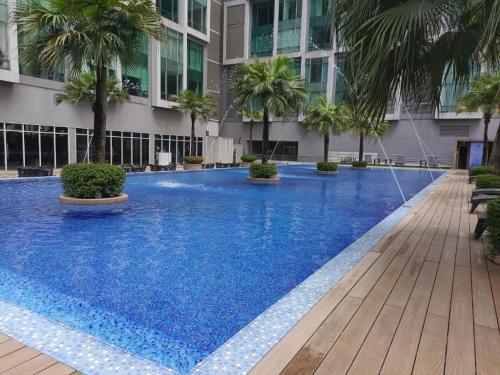 uma grande piscina azul com palmeiras em frente a um edifício em Soho Suites KLCC by Harry em Kuala Lumpur