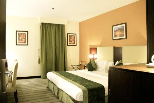 Business Inn Olaya في الرياض: غرفة الفندق بسرير كبير ومكتب