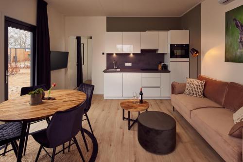 a kitchen and living room with a table and a couch at Hofparken De Bergvennen in Lattrop