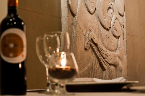 a glass of wine sitting next to a bottle of wine at Catalonia Conde de Floridablanca in Murcia
