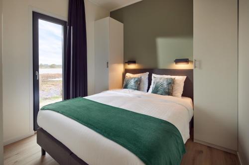 a bedroom with a large bed with a large window at Hofparken De Bergvennen in Lattrop