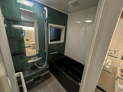 a bathroom with green walls and a shower with a mirror at Kototoki - En - in Gotsu