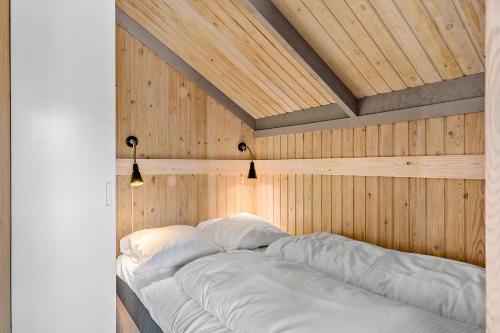 a bed in a room with a wooden wall at First Camp Råbjerg Mile - Skagen in Skagen