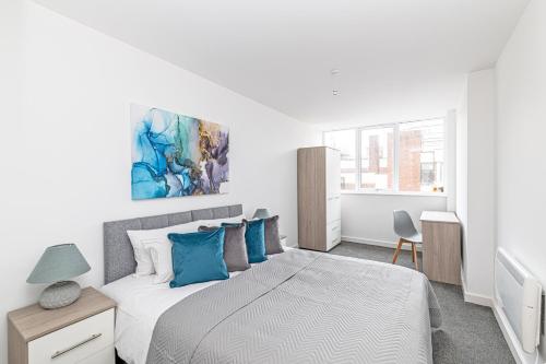 1 dormitorio blanco con 1 cama grande con almohadas azules en Winckley House Serviced Apartments in Preston, en Preston