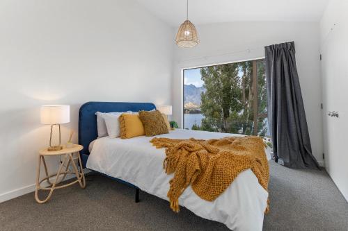 um quarto com uma cama azul e uma grande janela em Spacious relaxing home em Queenstown