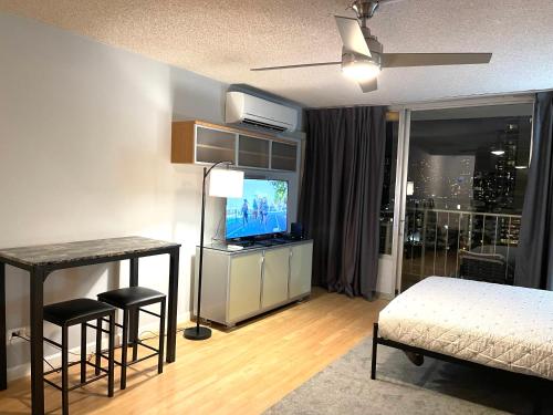 um quarto com uma cama, uma televisão e uma mesa em Marine Surf em Honolulu