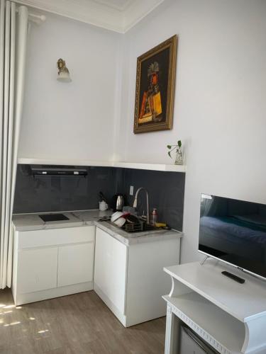 a white kitchen with a sink and a tv at Le Petit Paris Dalat Hotel in Da Lat