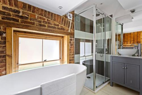 a bathroom with a white tub and a brick wall at Luxurious Victorian, a few minutes from the beach in Hollington