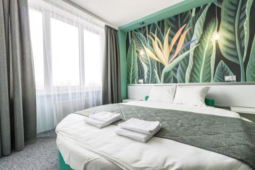 a bedroom with a large bed with a tropical wallpaper at Art Hotel Palma in Lviv