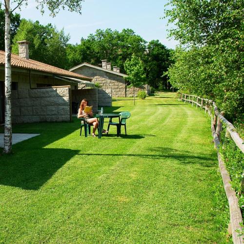 a woman sitting at a picnic table in the grass at Bungalows - Serra do Gerês in Campo do Gerês