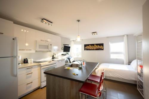 a kitchen with a sink and a bedroom with a bed at Le Chic-Urbain in Rouyn