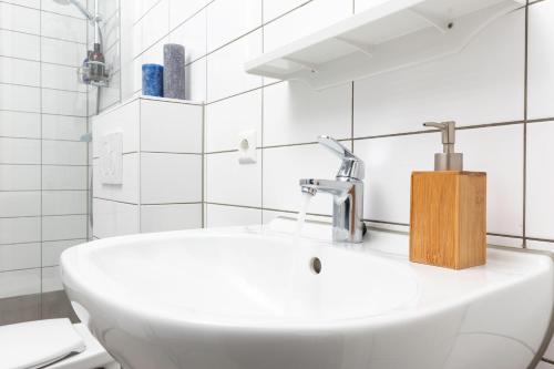 a white sink in a bathroom with white tiles at Lux Loft Apt View Walk city center sunny balcony XL Family Delft in Delft