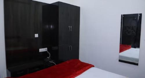 a bedroom with a black cabinet and a mirror at Hotel Shivam Inn Party Palace By WB Inn in Agra