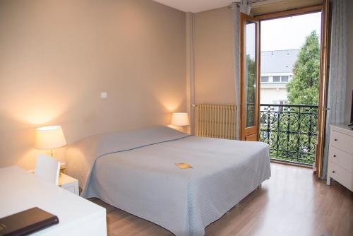 a bedroom with a white bed and a balcony at Hôtel Gallia in Aix-les-Bains