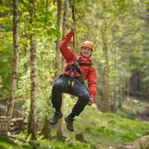 a man hanging on a zip line in the woods at Crieff Hydro Self Catering in Crieff