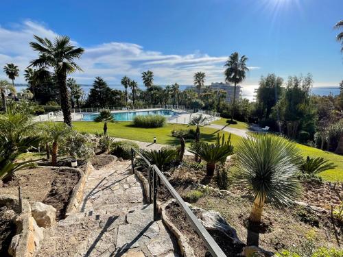 un jardin avec des palmiers et une piscine dans l'établissement La Mirandole by Connexion, à Vallauris