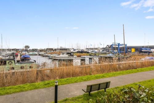 a park bench next to a marina with boats at Cosy tiny houseboats near beach and restaurants by Weltevreden Experience in Zeewolde