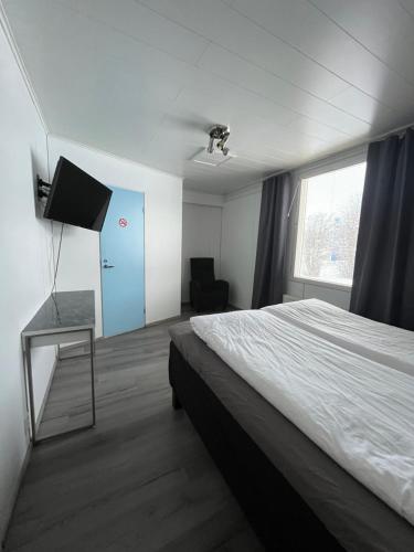 a bedroom with a bed and a tv and a chair at SEO Motel Alavieska in Alavieska