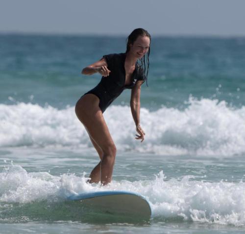 a woman riding a wave on a surfboard in the ocean at D' Art VILLA RETREAT AND SPA in Tangalle