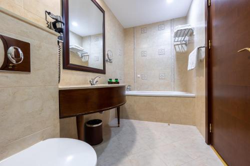 a bathroom with a sink and a toilet and a tub at Primoretz Grand Hotel & Spa in Burgas City