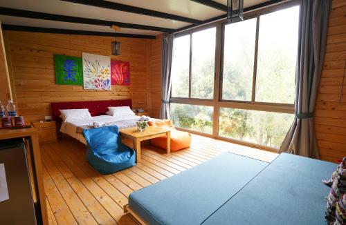 a bedroom with a bed and a large window at Blue Jay Valley in Jezzîne