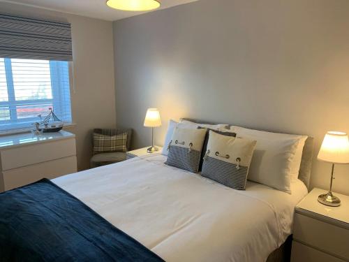 a bedroom with a white bed with pillows and a window at Kintyre Apartment in Ayr
