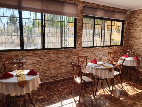 een eetkamer met tafels, stoelen en ramen bij The VIP Luxury Lounge Hotel in Kisumu